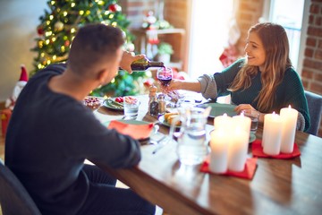 Young beautiful couple smiling happy and confident. Eating food celebrating christmas at home
