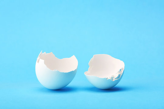 One white broken egg shell on blue background