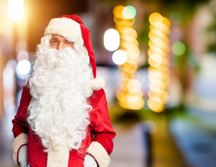 Middle age handsome man wearing Santa Claus costume and beard standing winking looking at the...