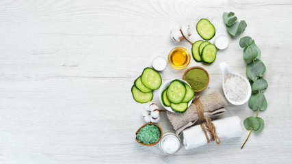 Obraz na płótnie Canvas Natural cosmetics from green cucumber, on white wooden background. The concept of cosmetics and spa. Top view. Free copy space.