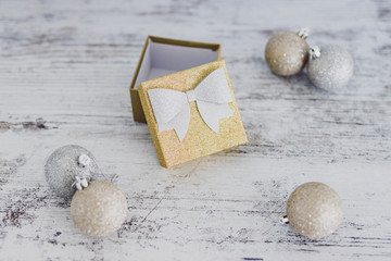 Christmas gift box with baubles around it wth gold and silver colors on wooden desk