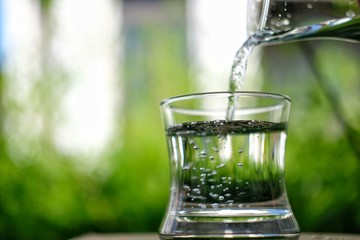 glass of water with ice on green background