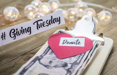 Giving Tuesday donate charity concept with text and cash on wooden board