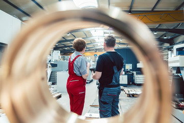 Workers standing on the factory floor seen through a workpiece