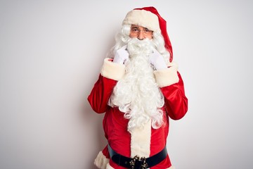 Middle age handsome man wearing Santa costume standing over isolated white background Smiling with open mouth, fingers pointing and forcing cheerful smile