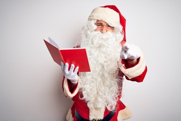 Naklejka premium Middle age man wearing Santa Claus costume reading book over isolated white background pointing displeased and frustrated to the camera, angry and furious with you