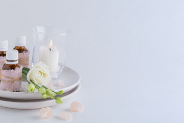 Spa composition with oils, sea salt, candles and a branch of white eustoma on a white background
