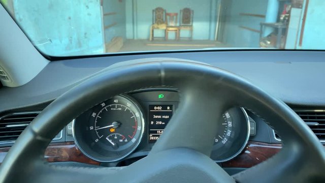 POV driver behind the wheel reversing car out of garage.