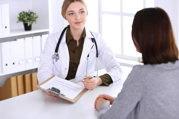 Young woman doctor and patient at medical examination in hospital office. Khaki colored blouse of therapist looks good. Medicine, healthcare and doctor's appointment concept