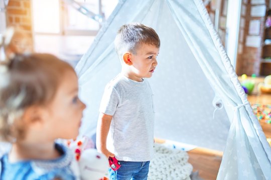 Adorable toddlers smiling happy. Standing playing around lots of toys at kindergarten
