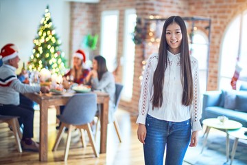 Young beautiful chinese woman smiling happy and confident. Standing with smile on face celebrating Christmas with friends at home