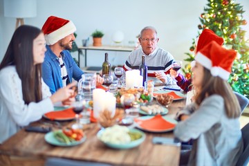 Beautiful family wearing santa claus hat meeting smiling happy and confident. Eating roasted turkey celebrating Christmas at home