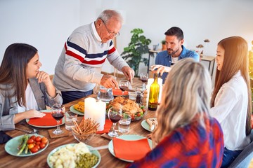 Beautiful family meeting smiling happy and confident. Carving roasted turkey celebrating Christmas at home
