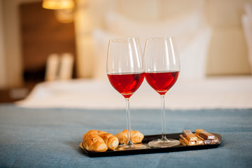 two glasses of wine and chocolate on the bed