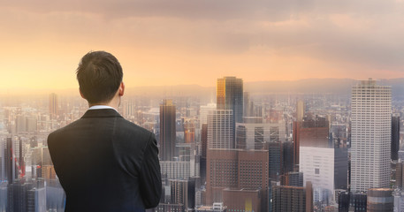 Fototapeta na wymiar Businessman looking at futuristic city in sunset. Business concept