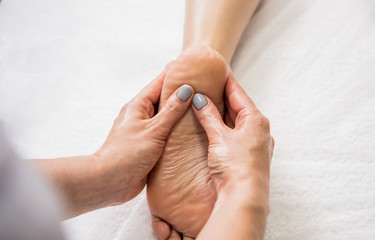 Beautiful young woman enjoying foot massage in spa salon. Cosmetology