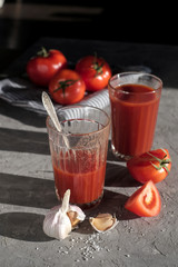 Glass of fresh tomato juice, tomatoes and garlic  on a dark   board