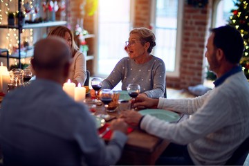Family and friends dining at home celebrating christmas eve with traditional food and decoration, all sitting on the table together