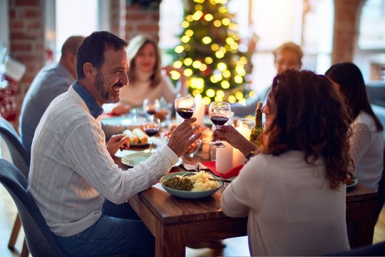 Family and friends dining at home celebrating christmas eve with traditional food and decoration, all sitting on the table together