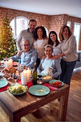 Family and friends dining at home celebrating christmas eve with traditional food and decoration, taking picture all together