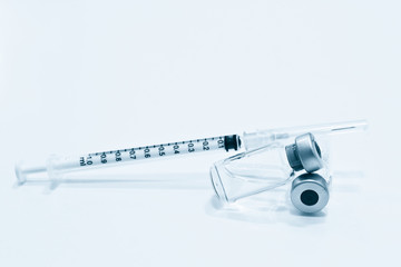 Vial of drugs or vaccine and 1 ml plastic syringe with needle isolated on the white background, blue tone color