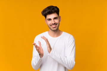 Young man over isolated orange background applauding after presentation in a conference