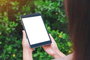 Mockup image of a woman holding black tablet pc with blank white desktop screen in the park