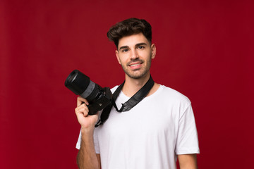 Fototapeta na wymiar Young man over isolated background with a professional camera