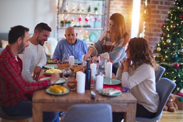 Beautiful family smiling happy and confident. Carving roasted turkey celebrating Christmas at home