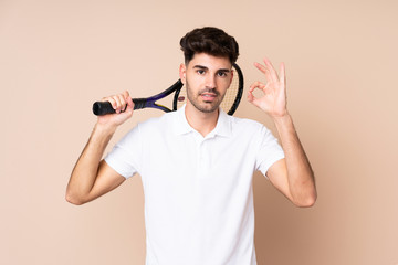 Young man over isolated background playing tennis and making OK sign