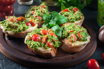 Bruschetta with fresh pesto, mozzarella and cherry tomatoes on cutting board