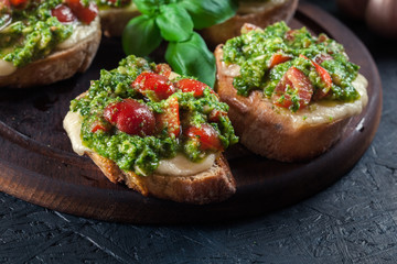Bruschetta with fresh pesto, mozzarella and cherry tomatoes on cutting board