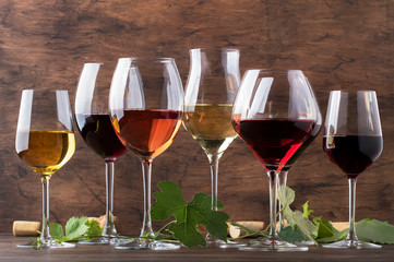 Wine set. Red, white and rose wine in assortment in wineglasses. Wine tasting, vintage wooden background, selective focus, copy space