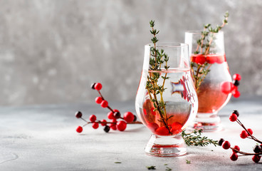 Winter alcoholic cocktail with red berries, liquor, gin, thyme and vodka for Christmas or New Year. Holiday table setting - obrazy, fototapety, plakaty