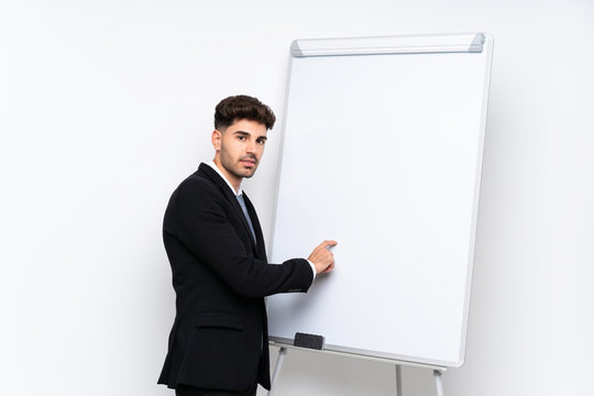 Young businessman giving a presentation on white board giving a presentation on white board and writing in it