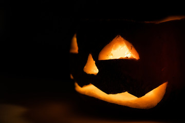 Fototapeta premium Alone head of the pumpkin inside the dark room. Only candle make a light during october halloween night.