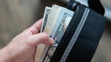 hundred dollar bills are in the wallet. Man's hands divide dolar bills.