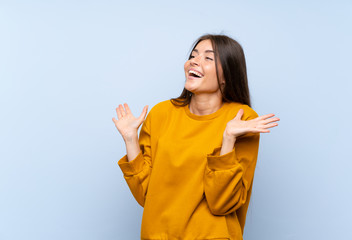 Caucasian young woman over isolated blue wall with surprise facial expression