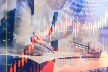 Double exposure of hands making notes with forex chart huds. Stock market concept.