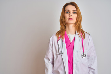 Redhead caucasian doctor woman wearing pink stethoscope over isolated background Relaxed with serious expression on face. Simple and natural looking at the camera.