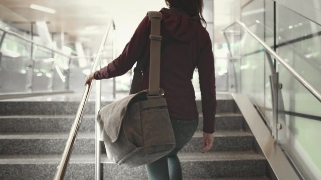 Woman Go Up on Stairs at International Airport. Back View of Girl Carrying Shoulder Bag. Transit Passenger Walking on Staircase. Corridor to Modern Terminal Lounge. Footage Shot in 4K