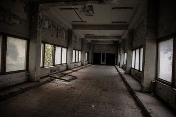 Dark, spooky tunnel, corridor with large windows at the end in abandoned building
