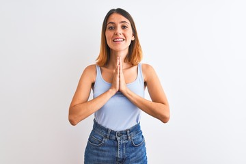 Obraz premium Beautiful redhead woman standing over isolated background praying with hands together asking for forgiveness smiling confident.