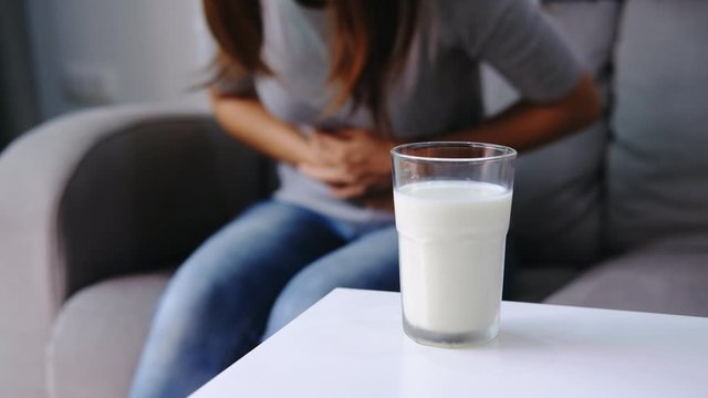 Woman having bad stomach ache with a glass of milk, Lactose intolerance, health care concept