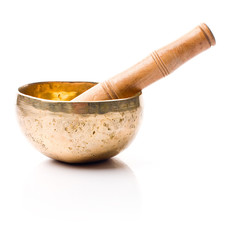 Closeup of a singing bowl and its mallet on a white backround