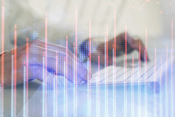 Double exposure of graph with man typing on computer in office on background. Concept of hard work.