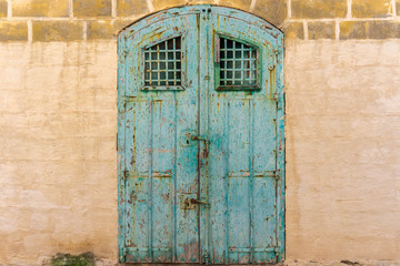 Vintage old warehouse blue wooden door with ancient limestone brick wall