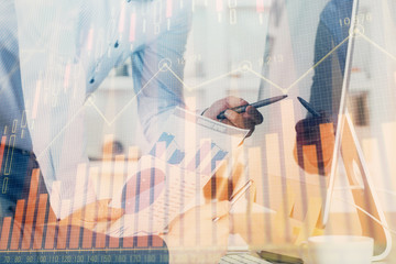 Double exposure of chart with businessman typing on computer in office on background. Concept of...