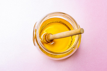 Honey with honey dipper on pink table