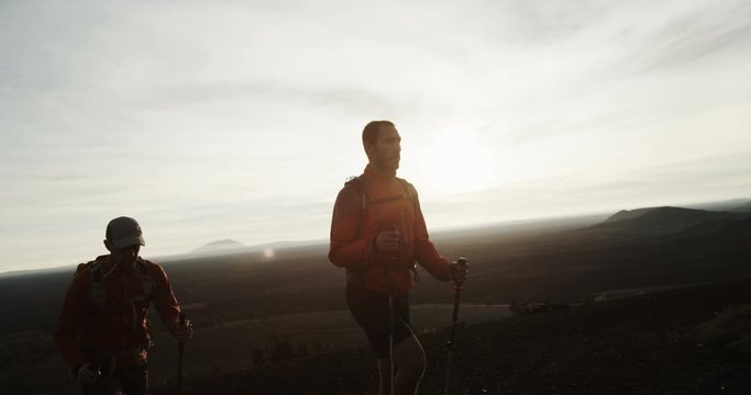 Two hikers silhouetted against rising sun in the desert during a race slow motion